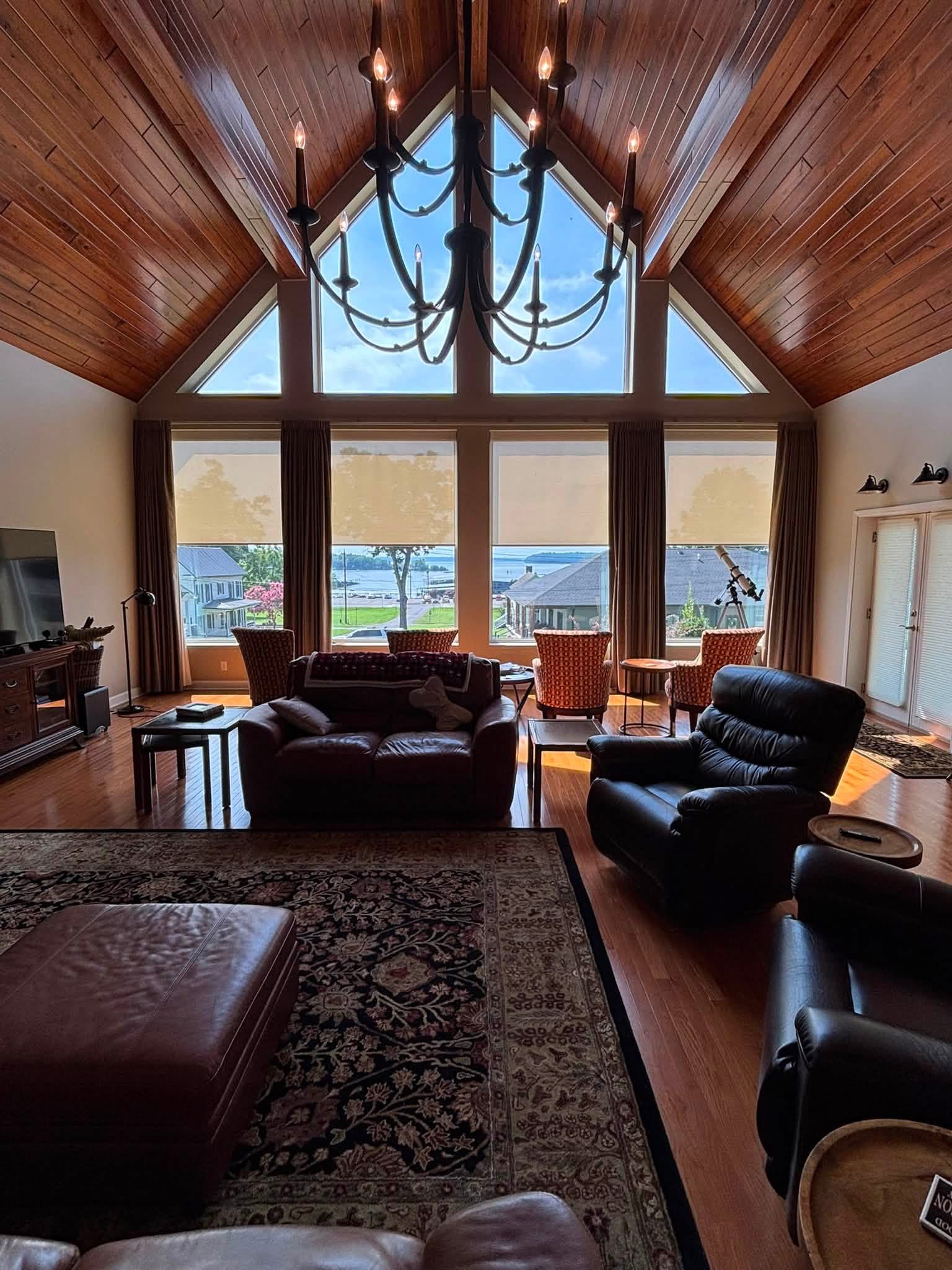 Roller shades across tall lakefront living room windows